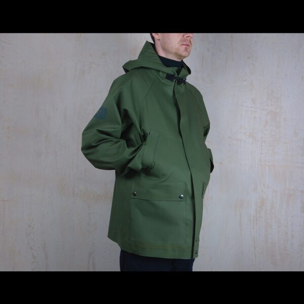 Logo-Side-View-Of-Model-Wearing-Waterproof-Green-Rain-Parka-By-rainford-Apparel