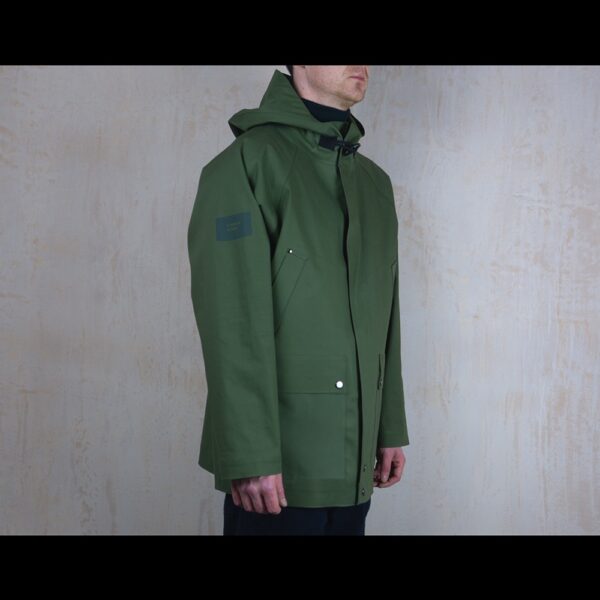 Logo-Side-View-Of-Model-Wearing-Waterproof-Green-Rain-Parka-By-Rainford-Apparel