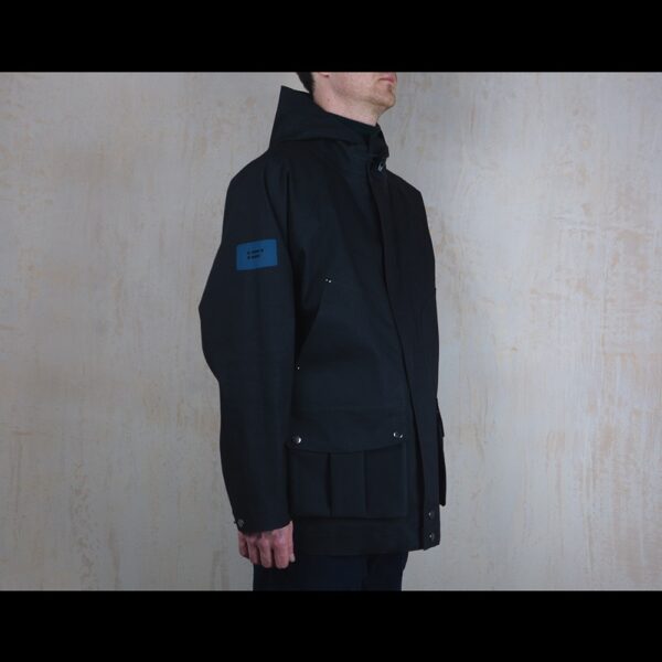 Logo-Side-View-Of-Model-Wearing-Waterproof-Houndstooth-Print-Rain-Parka-By-Rainford-Apparel